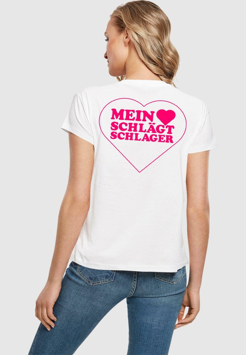 Tricou alb din bumbac, cu un grafic mare în formă de inimă roz și textul "MEIN ♥ SCHLÄGT SCHLAGER" pe spate. Mâneci scurte și croială standard.