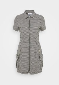 Lyhythihainen mekko mustavalkoisella koiranhammaskuvioinnilla, jossa on vetoketju edessä, kaulus ja kaksi sivutaskua. Valmistettu kudotusta kankaasta.