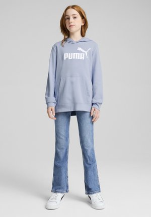 Šviesiai mėlynas džemperis su baltu "PUMA" logotipu ir kengūros kišene, derinamas su platėjančiomis mėlynomis džinsinėmis kelnėmis ir baltomis sportbačiais. Lygus medžiagos paviršius.