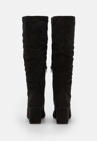 Schwarze Wildleder-Stiefel bis zum Knie mit runder Zehenform und klobigem Absatz, die eine glatte Textur und seitliche Reißverschlüsse für ein einfaches An- und Ausziehen bieten.