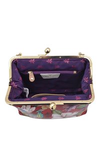 Rode handtas met bloemenpatroon en een gouden metalen sluiting, met een paarse binnenkant versierd met kleine roze bloemen en een ritsvak.