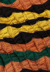 Strickstoff mit einem strukturierten Karomuster in abwechselnden Streifen von Schwarz, Gelb, Grün, Orange und Braun.