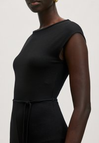 Schwarzes, geripptes Kleid mit taillierter Passform, kurzen Ärmeln und einem Kordelzug in der Taille. Glatter Stoff mit minimalistischem Design.