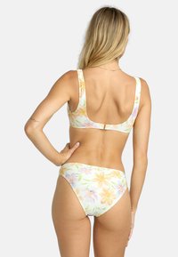 Blommig bikini-set med ett mönster i pastellgul, rosa och grön; texturerat tyg; breda remmar; och knäppning på baksidan.