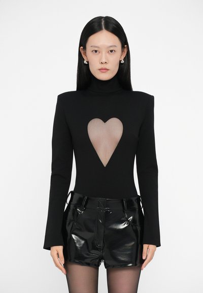 Black fitted bodysuit with long sleeves featuring a heart-shaped transparent cutout at the chest, paired with glossy black shorts.