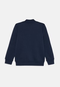 Sweatshirt bleu marine avec un col montant, des manches longues, des poignets et un ourlet côtelés. Texture de tissu lisse sans motifs ni accents visibles.
