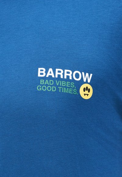 Μπλε ύφασμα με λευκό κείμενο "BARROW", πράσινο κείμενο "BAD VIBES, GOOD TIMES" και κίτρινο πρόσωπο γελαστό με δόντια βρυκόλακα.