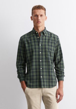 Men's button-up shirt in dark green and navy plaid. Features long sleeves, a breast pocket, and white buttons. Smooth cotton fabric.