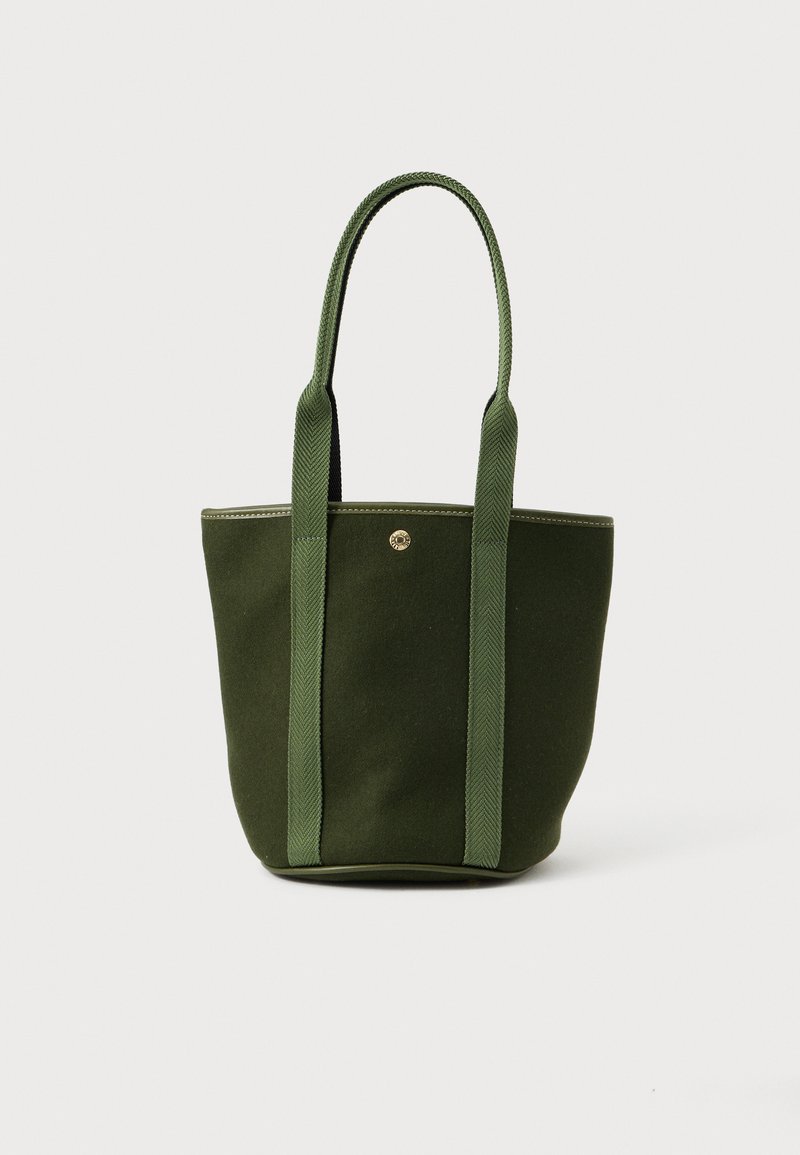 Borsa a mano in cotone verde con manici testurizzati abbinati, dettaglio circolare in metallo sulla parte anteriore e design strutturato.
