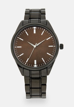 Montre de poignet en métal noir avec un boîtier rond, un cadran texturé marron, des index horaires blancs et des aiguilles argentées. Présente un bracelet segmenté brillant.