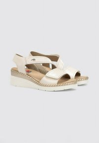 Sandalias de cuña en cuero crema. Presentan punta abierta, correa ajustable y detalle de costura a lo largo de la suela. Diseño ligero y casual.