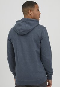 Sweatshirt à capuche bleu marine avec un tissu texturé. Comprend une poche фронтале, des poignets côtelés et un ourlet, conçu pour un usage décontracté.