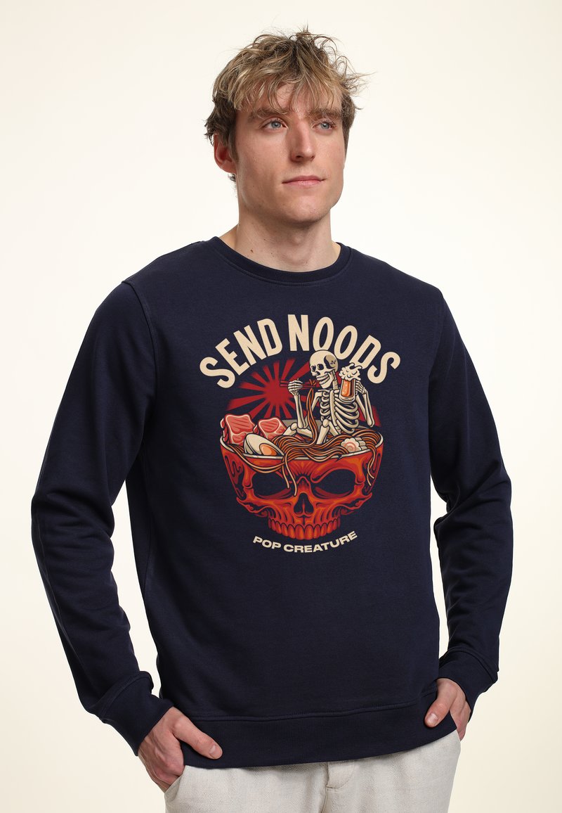 Marineblaue Sweatshirt mit grafischem Design, das einen Totenschädel und Skelette in einer Nudel-Schüssel zeigt. Hergestellt aus weichem Material mit rundem Halsauschnitt und gerippten Bündchen.