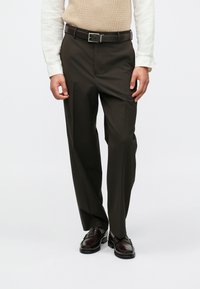 Σκούρες καφέ ψηλόμεσες παντελόνες με ίσια γραμμή, διαθέτοντας μια ζώνη με ορθογώνια ασημένια αγκράφα και λείο υφασμάτινο σχέδιο.