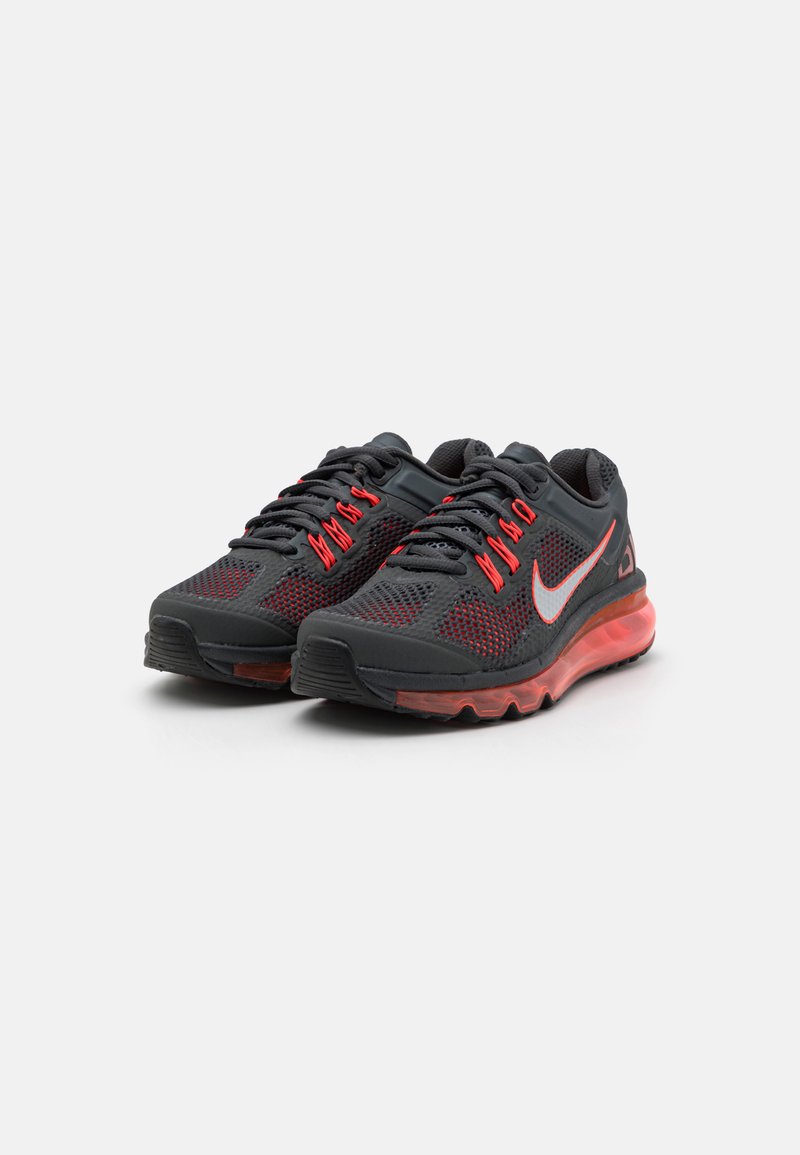 Zapatillas deportivas negras y rojas con parte superior de malla, cuello acolchado y suela gruesa y translúcida. Presenta cordones y logo en contraste.