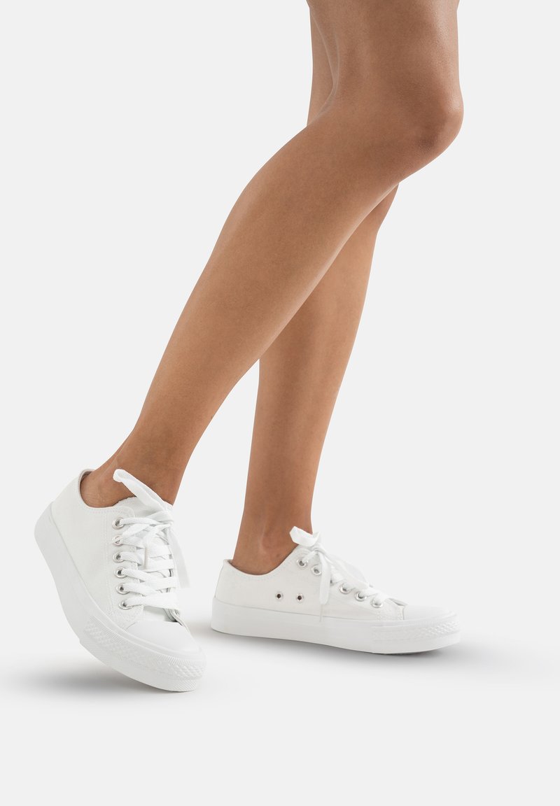 Białe płócienne trampki o teksturowanym wykończeniu, z wiązaniem i niskim profilem. Posiadają zaokrąglony czubek oraz minimalistyczne akcenty w postaci oczek.