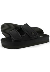 Black slide sandals made of synthetic material, featuring two adjustable Velcro straps, a textured black sole, and a cushioned footbed.