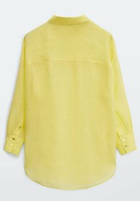 Chemise en lin jaune avec col, manches longues, poignets à boutons et coupe décontractée. Le dos présente des coutures minimales et une texture lisse.