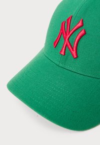 Grønn caps laget av teksturert stoff, med en iøynefallende brodert rød NY-logo på fronten, samt en buet visir og sydd detaljer.
