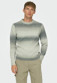 Maglione a maglia grigio chiaro con una gradazione dal grigio scuro al grigio chiaro, polsini e orlo a costine, collo rotondo, texture liscia e maniche lunghe.