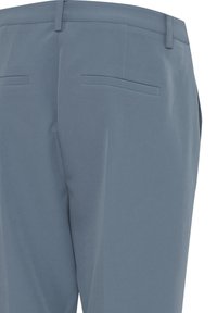 Pantaloni grigi su misura con una texture liscia, tasche posteriori piatte e design a gamba dritta. Nessun dettaglio di marchio o ferramenta visibile.