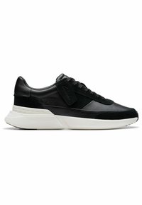 Zapatilla de cuero y ante negro con una gruesa suela blanca, que presenta un diseño de cordones y un logo en el panel lateral.