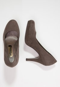 Bruna mockaskor med hög klack, rund öppen tå, slät insida och en smal klack, med minimala sömnadsdetaljer.