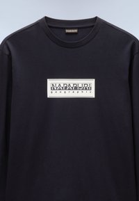 Black long-sleeve t-shirt made of cotton, featuring a rectangular white graphic with "NAPAPIJRI geographic" text in a layered font style.