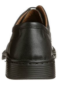 Zapato de cuero negro con un acabado suave, tacón redondeado y costuras detalladas; presenta una suela de goma ligera y estriada.