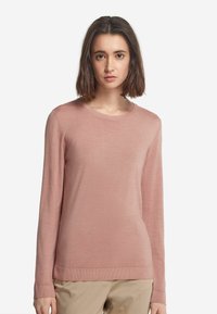 Ljust rosa långärmad tröja i mjukt stickat tyg med rund halsringning och ribbade muddarna och nederkant, i kombination med beige byxor.