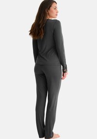 Ensemble de haut à manches longues gris et de pantalon assorti, fabriqué dans un matériau doux, avec une coupe décontractée et des accents en dentelle sur les manches.