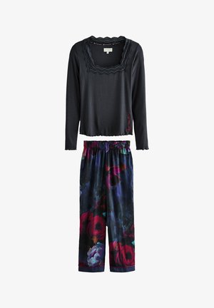 Maglia nera a maniche lunghe con bordi in pizzo e ricami rossi, abbinata a pantaloni della pigiama blu scuro con motivo floreale e vita elasticizzata.