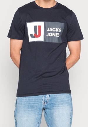 Granatowa bawełniana koszulka z okrągłym dekoltem, z prostokątną grafiką przedstawiającą "JJ" w kolorze czerwonym i czarnym oraz napisem "JACK & JONES" w białym.