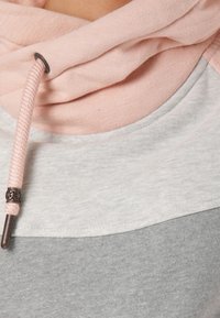 Felpa grigia con collo a drappeggio rosa. Presenta un tessuto morbido e texturizzato con un cordoncino e un accento metallico decorativo.