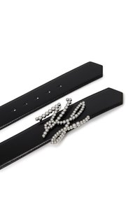 Čierny kožený opasok s plochým dizajnom, ktorý má ozdobu zo striebornej perly v slučkovom vzore ako dekoratívny akcent.
