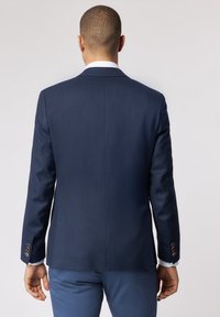 Marineblau strukturierter Blazer mit elegantem Design, taillierter Passform und Knopfakzenten an den Manschetten. Die Rückansicht zeigt klare Linien und keine Schlitze.