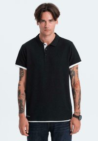 Černé polo tričko s krátkým rukávem, kontrastní bílý lem na rukávech a límci, a léga na tři knoflíky. Bavlněný materiál, pohodlný střih.