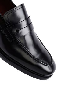 Schwarze Lederloafer mit einer glatten, glänzenden Oberfläche, detaillierten Nähten und einem Band an der Vorderseite. Leicht erhöhter Absatz und abgerundete Zehen.