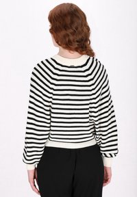 Maglione a righe bianco e nero in filato, con scollatura rotonda, spalle scese e polsini e orlo a costine. Design leggermente corto.