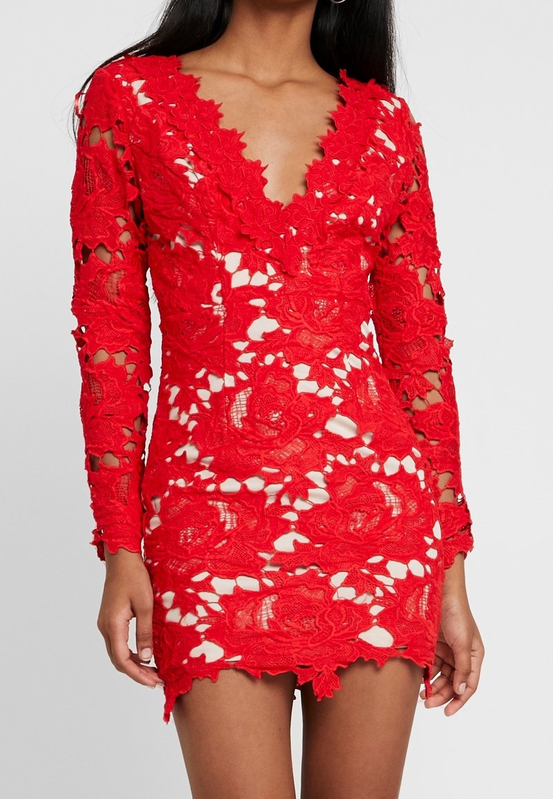 Red lace dress featuring long sleeves, a deep V-neck, and intricate floral patterns with cut-out details. Short hemline accentuates silhouette.