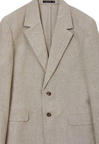 Blazer beige in lino con rever a spillo, due bottoni marroni e due tasche frontali. Etichetta con la scritta "CALLIOPE", taglia 50, con un tessuto testurizzato.