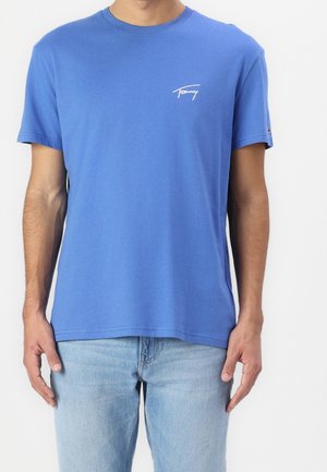 Modré bavlněné tričko s krátkými rukávy, kulatým výstřihem a bílým vyšitým logem na levé části hrudi. Volný střih.