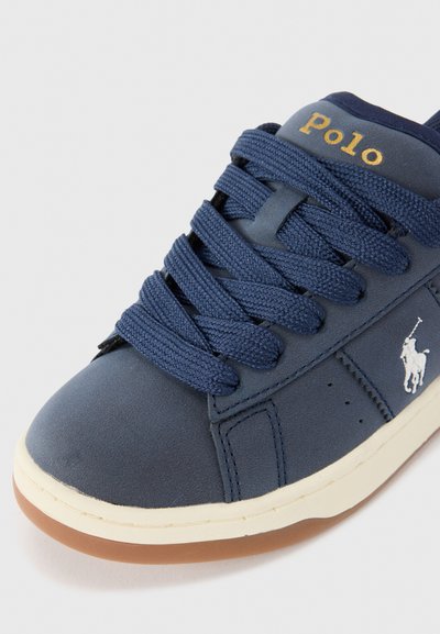 Mörkblå sneakrar i texturerad läder med vit gummisula, med ett guld "Polo"-logotyp och tjocka mörkblå snören. Förstärkt med en vit logodetalj.