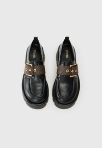 Sorte læder loafers med en tyk sål, med en brun mønstret rem og guldspænde detaljer; glat overflade med syninger.