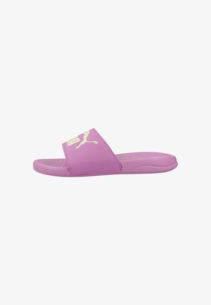 Sandalia tipo deslizador morada con suela acolchada y una tira ancha que presenta un logo blanco de Puma, vista de lado sobre un fondo blanco.