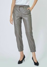 Graue Leder-Jogginghose mit elastischem Bund und Bündchen, ausgestattet mit Seitentaschen und einer Kordel für eine verstellbare Passform.