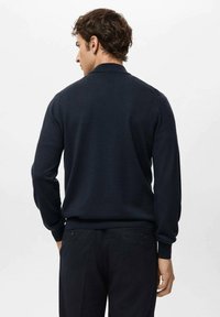 Granatowy dzianinowy sweter z długimi rękawami i kołnierzem, o gładkiej fakturze i ściągaczach na mankietach. Prezentowany od tyłu.