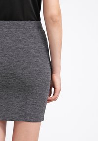 Grå stickad pennkjol med en åtsittande design, jämn textur och en medellång längd. Ingen synlig hårdvara eller mönster. Klassisk och mångsidig.