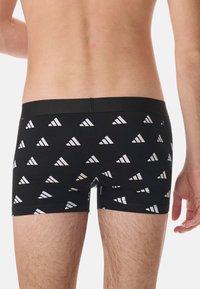 Boxer shorts noirs avec un motif triangulaire blanc répétitif, taille élastique et une coupe ajustée pour le confort et la flexibilité.
