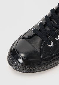 Czarne sneakersy z cholewką ze skóry i gumowym czubkiem, z czarnymi sznurowadłami i oczkami, teksturowana gumowa podeszwa z wzorem diamentowym.